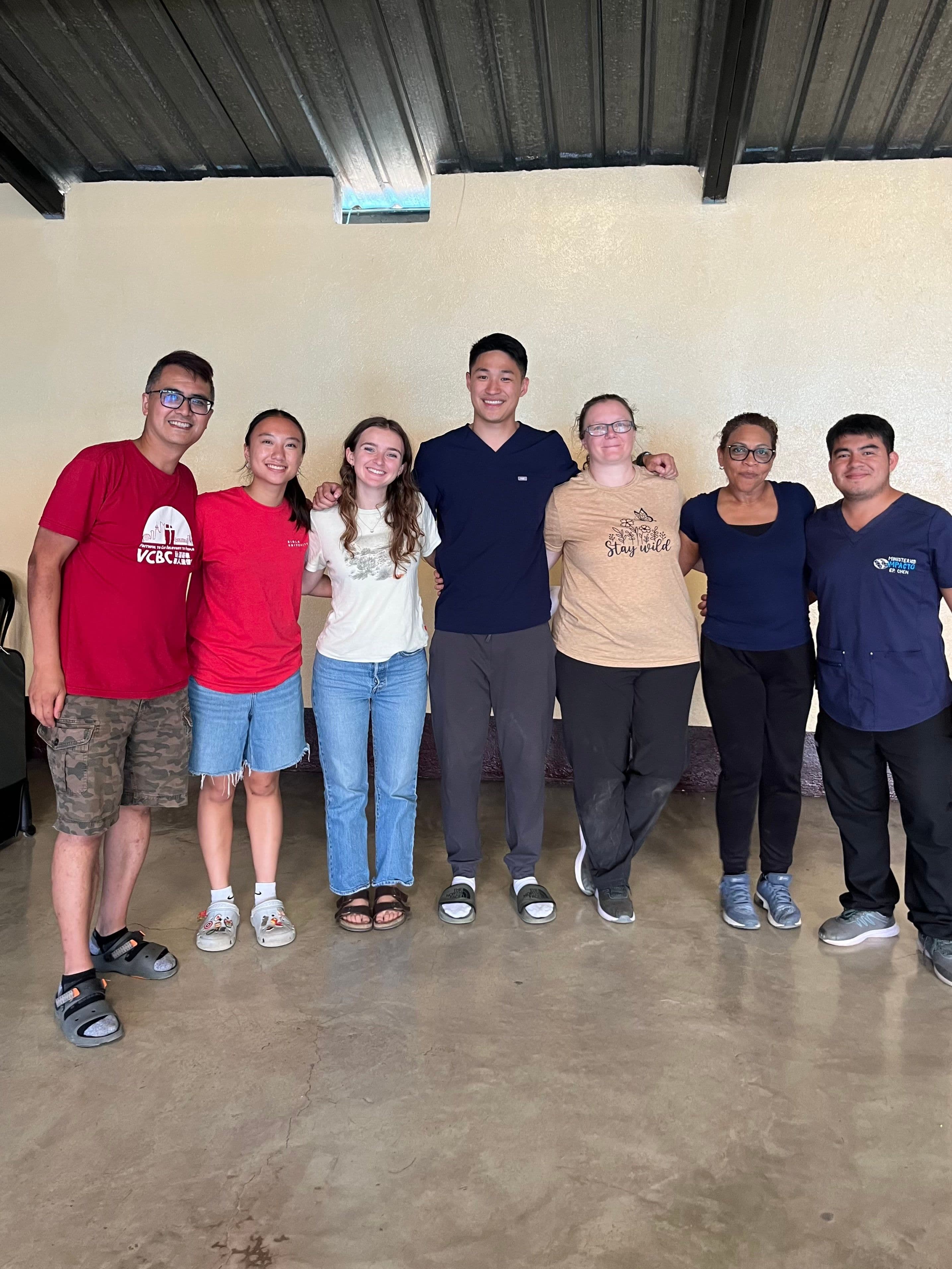 Leo with the volunteers and local staff he worked alongside in Tactic, standing arm in arm against a plain wall.