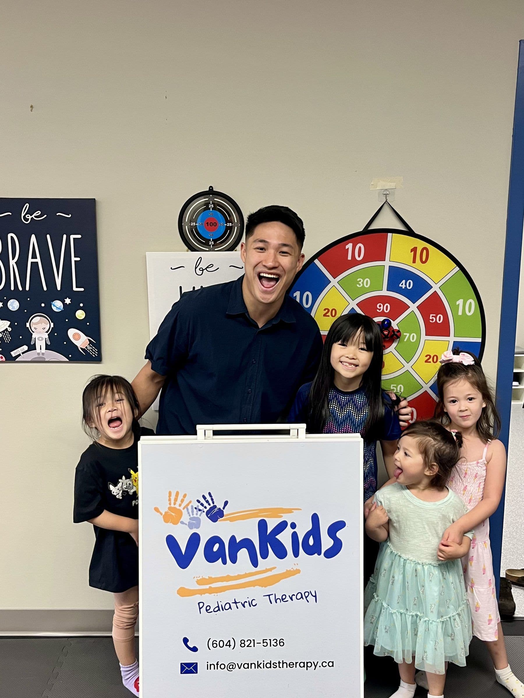 Leonardo Tam 与四名儿童站在 VanKids 诊所招牌旁。